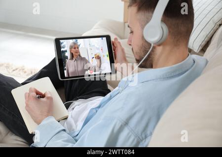 E-learning. Uomo che ha una lezione online con l'insegnante tramite tablet a casa Foto Stock