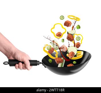 Uomo che getta gli ingredienti nel wok su sfondo bianco, primo piano Foto Stock