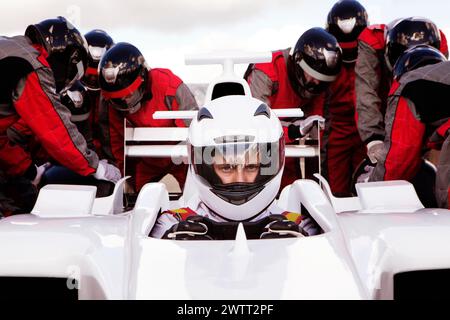 Pilota di auto da corsa concentrato sulla linea di partenza con un equipaggio pronto all'azione. Foto Stock