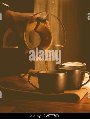 Una persona che versa caffè espresso in due tazze su un tavolo Foto Stock