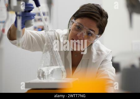 Attraente scienziata che esegue test con becher e peppet in laboratorio Foto Stock