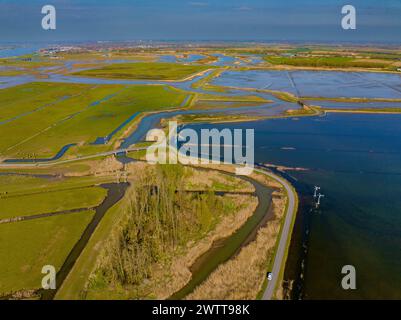 Vista aerea di un corso d'acqua serpentina che si snoda attraverso lussureggianti campi verdi sotto un cielo limpido Foto Stock