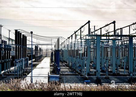 Sottostazione elettrica complessa all'alba con cablaggi e strutture industriali complessi Foto Stock