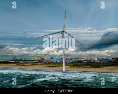 Una turbina eolica solitaria si erge su un cielo spettacolare in riva al mare. Foto Stock