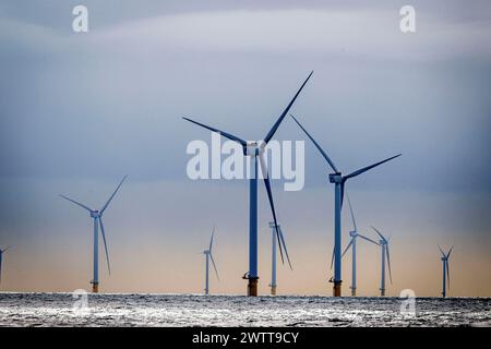 Turbine eoliche che torreggiano sull'oceano al crepuscolo Foto Stock