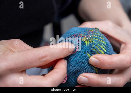 Curare i vestiti. Calza per riparazione e rimontaggio visibile. Cavolo vecchi calzini, riduzione degli sprechi, moda lenta. Concetto di riparazione, attenzione selettiva. Foto Stock