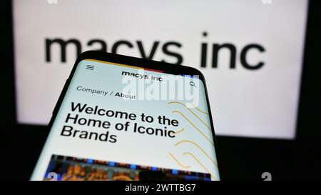 Telefono cellulare con sito web della società di vendita al dettaglio Macy's Inc. Davanti al logo aziendale. Mettere a fuoco in alto a sinistra sul display del telefono. Foto Stock