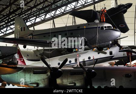 Gli specialisti dell'accesso alla fune industriale si lanciano al Royal Air Force Museum Midlands, a Cosford, vicino a Telford, nello Shropshire, per accedere a una mostra di aerei sospesi esposta nella National Cold War Exhibition, durante la pulizia e la manutenzione annuale di alto livello degli aeromobili. Data foto: Martedì 19 marzo 2024. Foto Stock