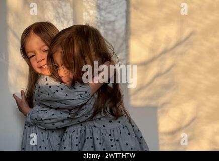 Ritratto di ragazze gemelle di razza mista che si abbracciano a vicenda. Felice giorno dei fratelli. Foto Stock