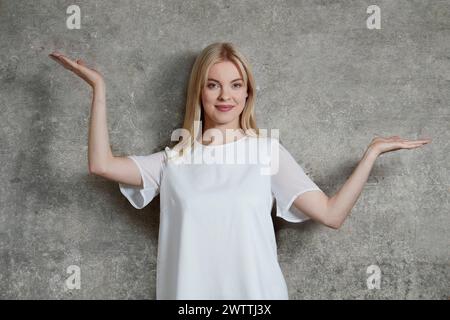 Donna in cima bianca che posa con le braccia sollevate Foto Stock