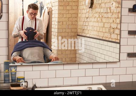 Barbiere che fa un taglio di capelli a un cliente Foto Stock