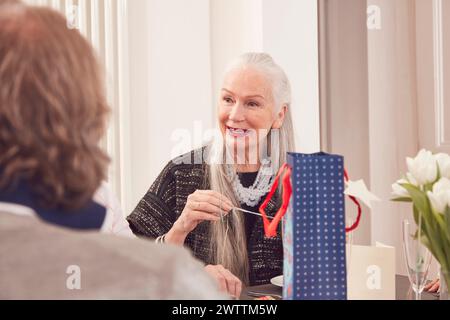 Donna anziana che si gode un pasto in compagnia Foto Stock