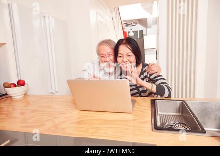 Una coppia anziana che usa un notebook in cucina. Foto Stock