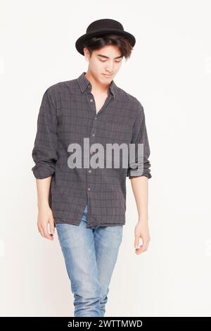 Giovane uomo elegante che posa in un abbigliamento casual con cappello Foto Stock