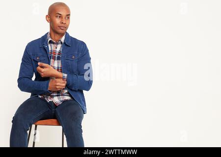 Uomo seduto su uno sgabello con un abbigliamento in denim Foto Stock