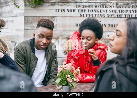 Gruppo di giovani impegnati in una conversazione a un tavolo Foto Stock