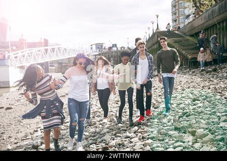 Gruppo di amici che camminano su una riva rocciosa del fiume Foto Stock