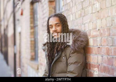 Uomo appoggiato a un muro di mattoni Foto Stock