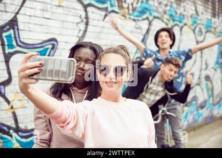 Amici che fanno un selfie contro il muro dei graffiti Foto Stock