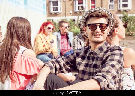Uomo sorridente con occhiali da sole in un gruppo di amici Foto Stock