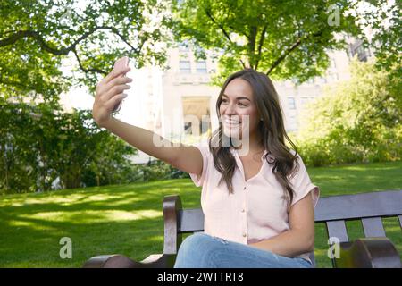 Una giovane donna che fa un selfie nel parco Foto Stock