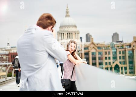 Fotografa che cattura un ritratto di donna con lo sfondo di un paesaggio urbano. Foto Stock