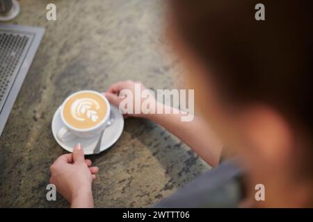 Persona che tiene una tazza di caffè con latte art Foto Stock
