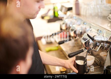 Il barista monta il latte in una macchina per il caffè Foto Stock