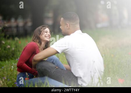 Coppia seduta insieme in un campo erboso Foto Stock