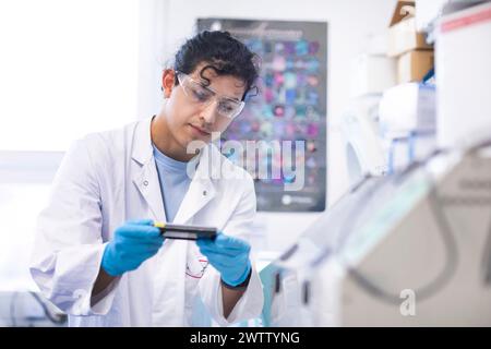 Scienziato che esamina un vetrino campione in laboratorio Foto Stock