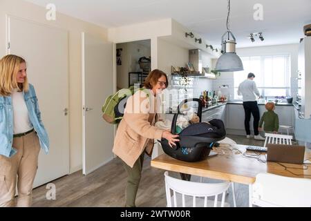La famiglia è impegnata con la routine quotidiana in un'accogliente cucina casalinga. Foto Stock