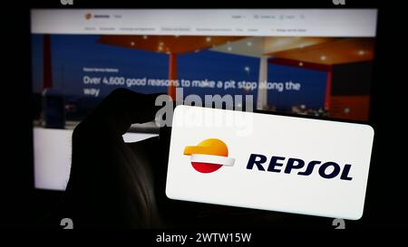 Persona che possiede uno smartphone con il logo della società petrolifera spagnola Repsol S.A. davanti al sito web. Mettere a fuoco il display del telefono. Foto Stock