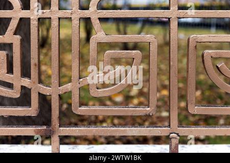 Reticolo di recinzione forgiato vintage dipinto in oro con motivo geometrico, foto da vicino all'esterno con messa a fuoco selettiva Foto Stock