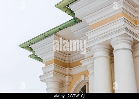 Portico classico con dettagli gialli e bianchi sotto il tetto verde. Pilastri e angoli Foto Stock