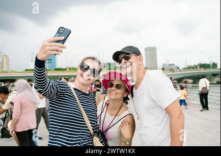 Famiglia felice che scatta selfie su smartphone nelle strade urbane Foto Stock