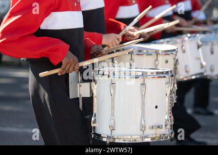 Gruppo di percussioni delle scuole superiori che mantiene il ritmo durante la partecipazione alla sfilata locale. Foto Stock