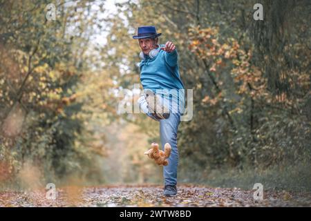 Un uomo migliore che calci un orsacchiotto in una foresta in autunno all'aperto Foto Stock