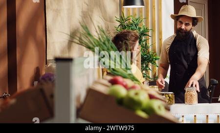 Il fornitore di supermercati Zero Waste saccheggia in background i prodotti alimentari dei clienti mentre acquista di più. I clienti fanno shopping in un negozio ecologico e rispettoso dell'etica Foto Stock