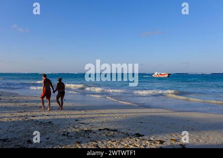 Una coppia camminava sulla spiaggia di Punta Cana sotto la luce del sole del tardo pomeriggio. Repubblica Dominicana Foto Stock