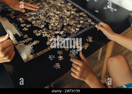 Un gruppo eterogeneo di persone riunite intorno a un tavolo, impegnandosi a risolvere insieme un puzzle impegnativo. Foto Stock