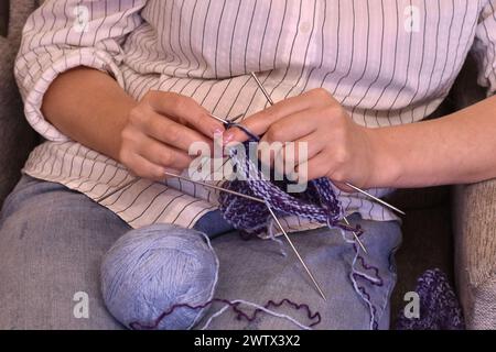 Primo piano con le mani di una giovane donna che lavora a maglia un calzino. Foto Stock