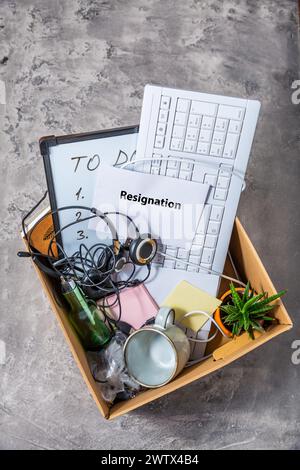 Lettera di dimissioni e scatola di cartone con tastiera, strumenti da ufficio e accessori personali Foto Stock