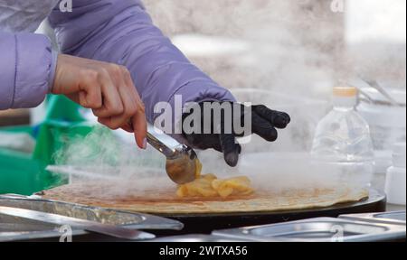 Il corpo centrale di uno chef che prepara crepes e pancake francesi al mercato agricolo di Praga, Naplavka, Repubblica Ceca Foto Stock