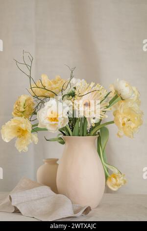 Mazzo di fiori gialli di gerbera, tulipani e ranunculus in un vaso su un tavolo con un tovagliolo Foto Stock