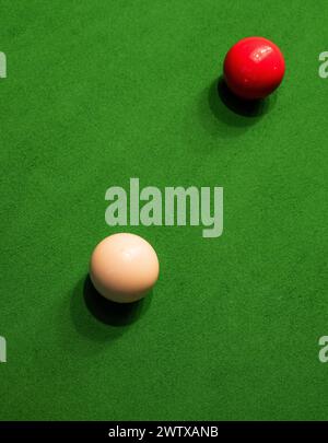 Palle da snooker rosse e bianche sul baize verde di un tavolo da snooker; una palla da cue e una palla da oggetti. Foto Stock