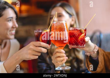 Due amici gioiosi - brindisi con vivaci cocktail - rinfrescanti bevande aperol spritz, atmosfera conviviale da bar, momenti di felicità e svago - c Foto Stock