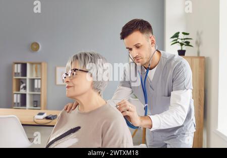 Medico o infermiere utilizza lo stetoscopio per esaminare paziente anziano durante il controllo medico Foto Stock