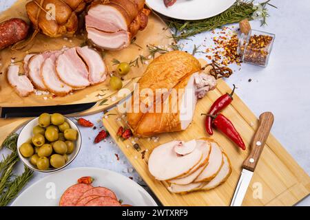 abbondanza di prelibatezze di carne su uno sfondo di cemento circondato da varie spezie ed erbe aromatiche, olive, peperoni Foto Stock