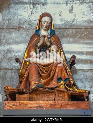 La Vergine, seduta sul sella curulis, ha le mani strette e il viso piegato sul bambino, che giace in grembo. Saturnino gatti. L'Aquila, Italia Foto Stock