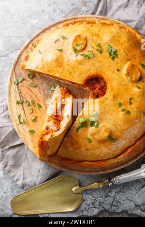 Empanada Gallega grande torta salata a due croste della Galizia ripiena di carne, peperoni rossi, pomodoro e un sacco di cipolla in primo piano sul tavolo. Foto Stock